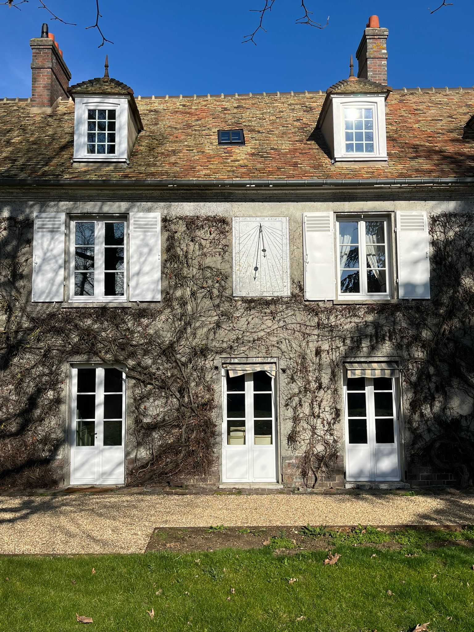Façade côté jardin — cadran solaire et vigne vierge