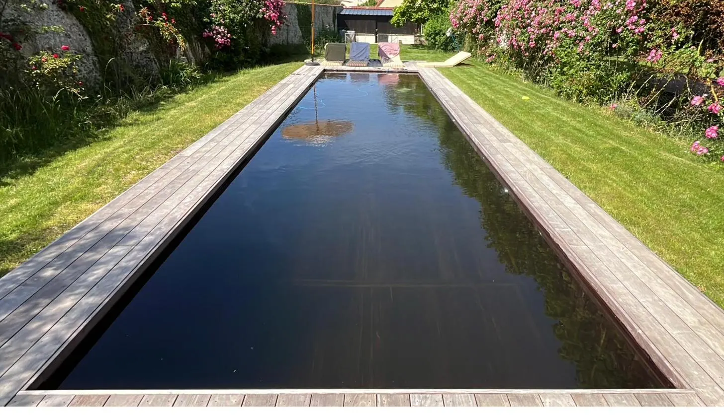 Piscine naturelle, eau sombre et plage de bois — Prieuré Saint-Bû